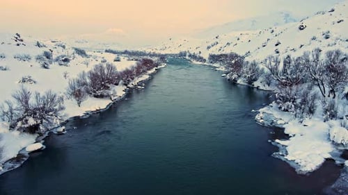 A river is frozen over and the sky is a beautiful orange color drone view