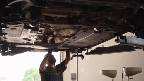 Auto Mechanic Works on Car Suspension in Repair Shop Fixes Vehicle Underside Inspects Springs Shock