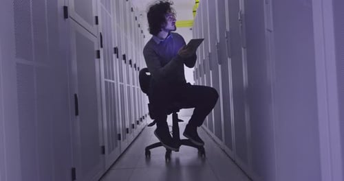 Ingénieur informatique ou spécialiste de la science des données travaillant sur une tablette dans une salle de serveurs dans un cloud moderne