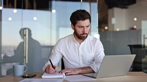 Businessman Working at Desk with Laptop in Modern Office