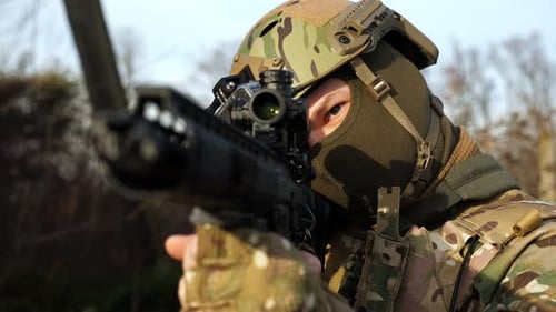Closeup of a Soldier in Military Uniform Holding a Machine Gun and Taking Aim