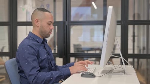 Man Working at Computer Rubs Temples