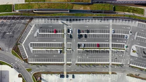 Aerial footage of a quiet car park from above showing a couple of cars driving around the car park