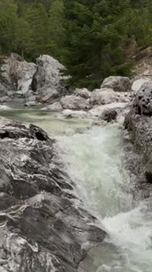 Vertikales Video Alpine Splendor Luftaufnahme des Wintergebirgswaldes mit Fluss und Wasserfällen