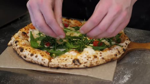 Closeup of a Chef Putting Arugula on a Pizza in a Traditional Italian Pizzeria