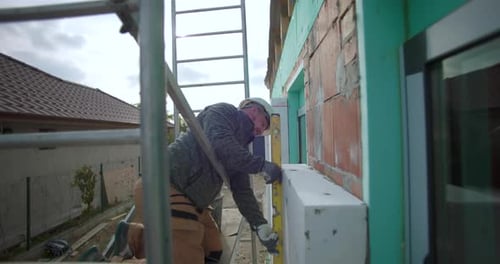 Medindo e nivelando o isolamento de paredes externas em andaimes durante a construção, construtor focado