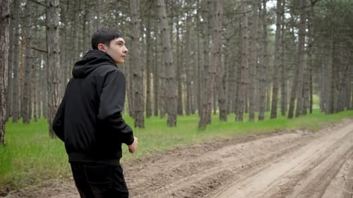 Ängstlicher nervöser Teenager rennt alleine durch den Wald Verängstigter ängstlicher Jugendlicher sprintet durch