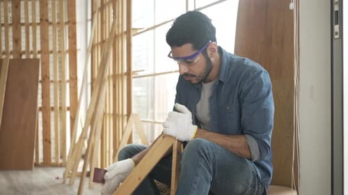 Man Sanding Wooden Frame in Bright Workshop