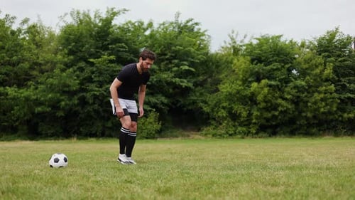 Fit Caucasian Male Bending to Stretching on Grassy Field with Soccer Ball Near