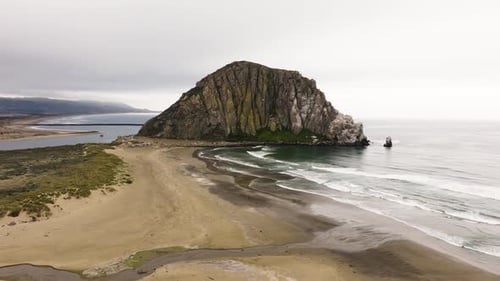 Aerial view of Morro Rock on a clear day approaching over the beach