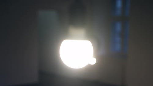 Two glowing bright lightbulbs hanging from the ceiling in a dark empty romm. Smooth camera sliding m