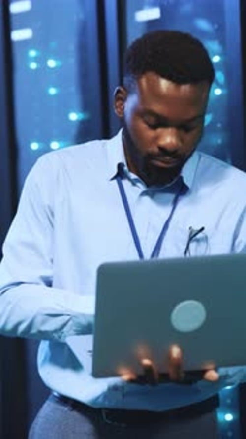 An IT Professional Actively Working on a Laptop Within a Sophisticated Data Center Environment