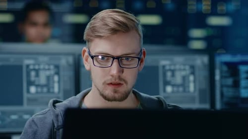 Retrato de um especialista em TI inteligente e bonito usando óculos funciona em um computador pessoal.
Na