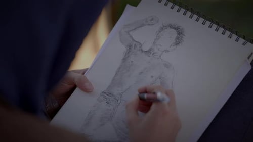 Young Creative Male Artist Drawing a Sketch Outside in the Park