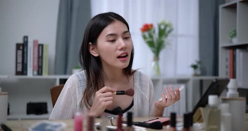 Hermosa bloguera asiática está mostrando cómo maquillar y usar cosméticos