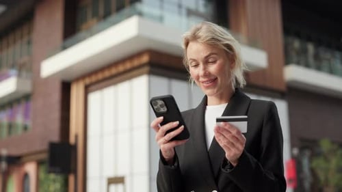 Portrait of Businesswoman Pays with Smartphone and Credit Card in Urban Area