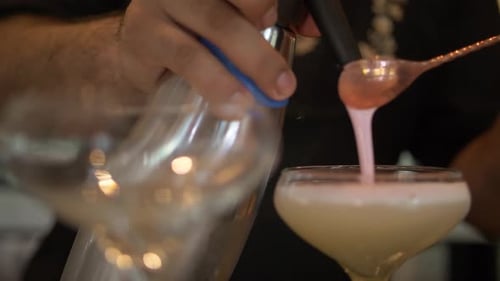 Bartender skillfully prepares a refreshing cocktail pouring drinks at a nightclub bar