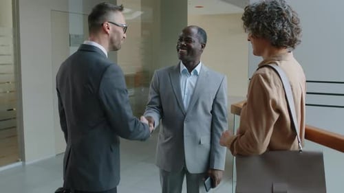 Business People Shaking Hands in Office Hallway