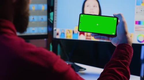 El editor de fotos usa un teléfono móvil con pantalla verde para ver un tutorial sobre cómo colorear fotografías correctas
