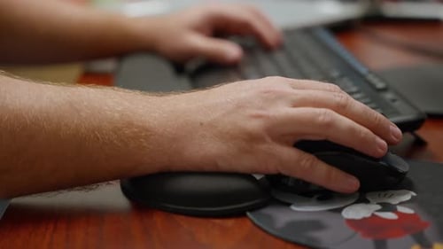 Hands using a keyboard and mouse at computer desk working in office