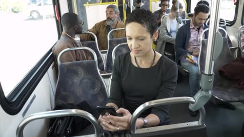 Woman Uses Smartphone on Bus with Other Passengers