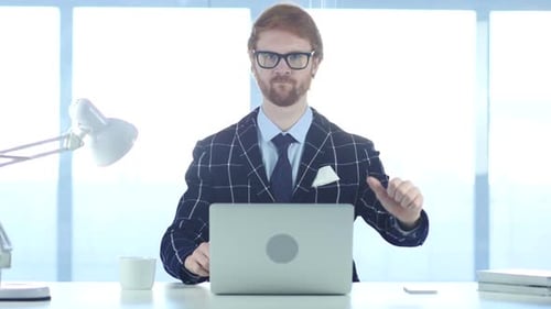 Man Gives Thumbs Up and Down at Desk
