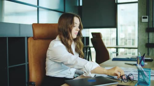 Young Woman Experiencing Stress in a Modern Office Environment While Working on a Laptop During a