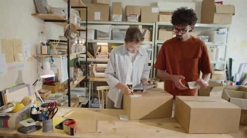 Mitarbeiter packen Bestellungen und benutzen Tablet im Lieferservice-Büro