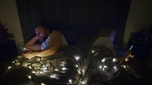 Couple in Bed Using Smartphones Back to Back