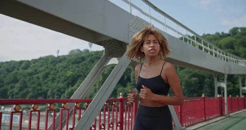 Young African American Woman Runner Jogging on City Bridge Outdoors