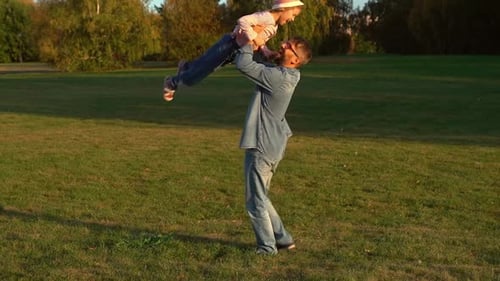 Familienspaziergang und lustiges Spielen im Freien im Herbstpark. Vater dreht Tochter herum