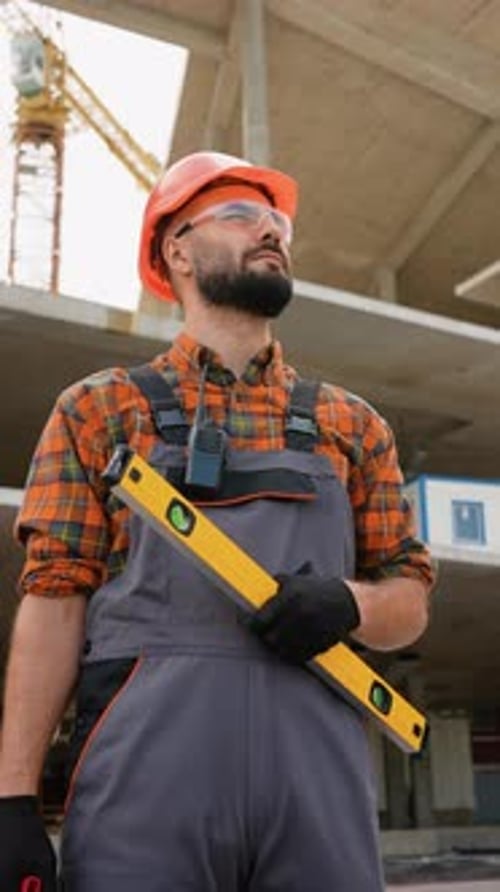 Construction Worker Holding Spirit Level at Building Site