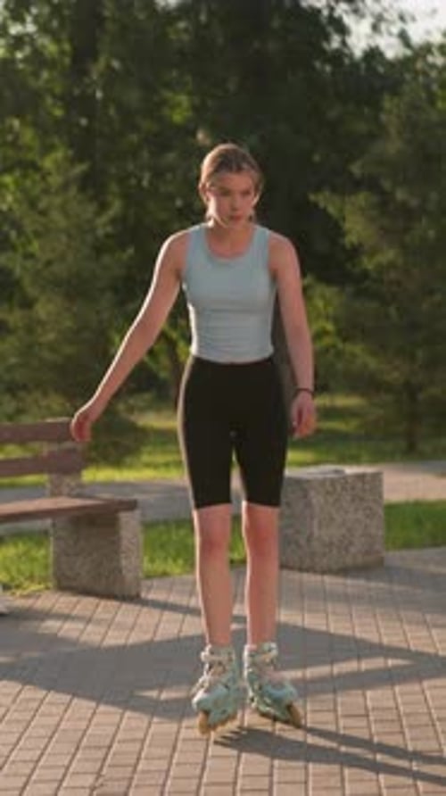 Young Lady Skating Outdoors in Park Surrounded By Greenery and Benches