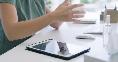 4k video footage of an unrecognisable businesswoman sanitising her digital tablet in a modern office