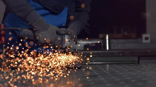 A man working with angle grinder, sparkles, super slow motion, close up