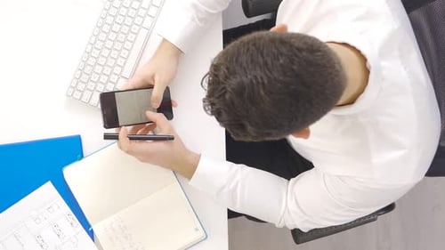 Vertikales Video eines Geschäftsmannes, der an dem Projekt arbeitet, betrachtet das Telefon und die Dokumente.