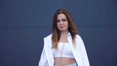 Portrait of young Caucasian girl in white shirt posing for camera. Close-up.