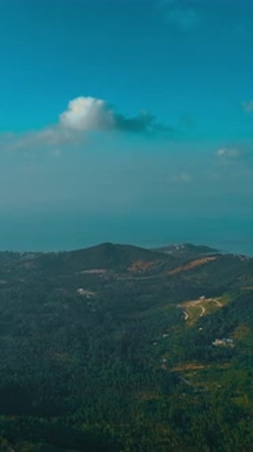 Scenic view of lush hills and coastline under bright blue sky