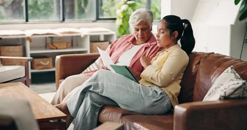Woman helping senior woman with tablet at home