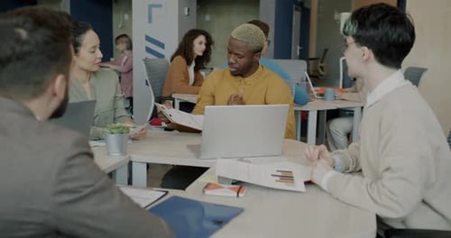 Group of Young Businesspeople Talking and Studying Charts in Modern Shared Office