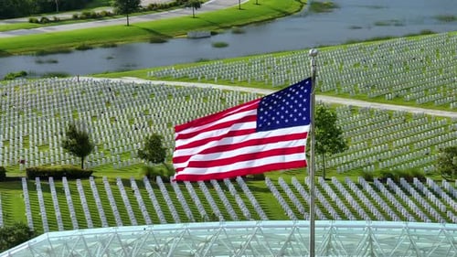 American Flag Waving Over Grassy Cemetery
