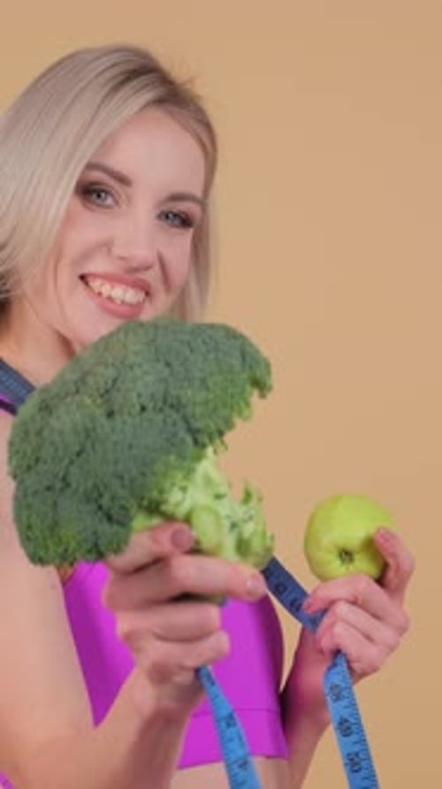 Smiling Woman Holding Broccoli and Apple
