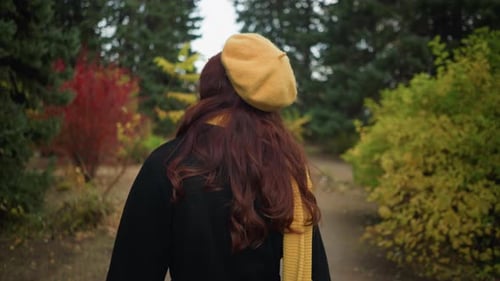 Artist Adjusts Hair While Walking in Autumn Park in Yellow Beret