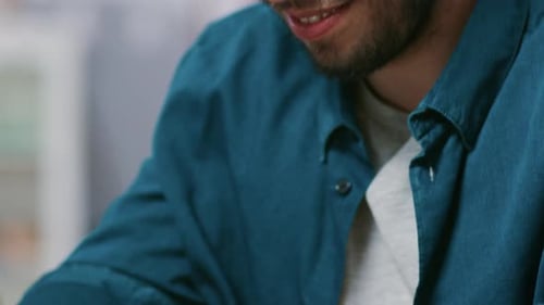 Close-up Elevating Shot of Handsome Man Typing on a Laptop and Smiling.