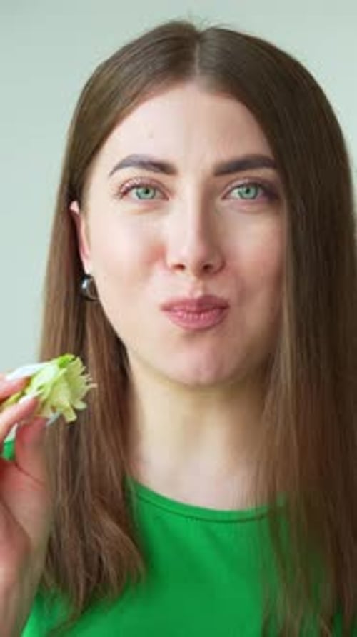 Joyful woman bites and chews juicy iceberg lettuce - 4K, close-up
