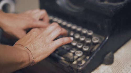 Nahaufnahme von Händen, die auf einer Vintage-Schreibmaschine tippen