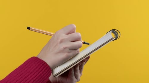 Hands of Woman Making Notes in Planner Holding Pen