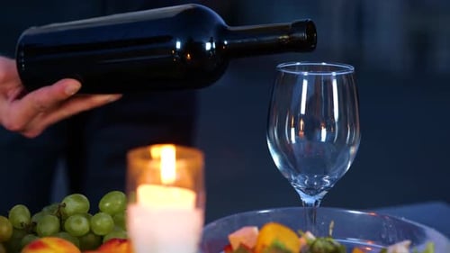Pouring Red Wine at Candlelit Romantic Dinner