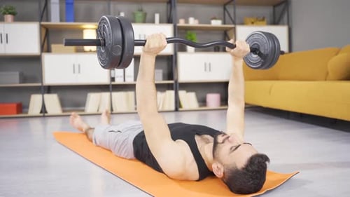 Man Lifting Barbell on Exercise Mat at Home