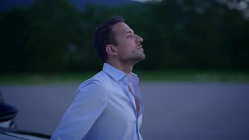 Man Leans on Car Hood at Night